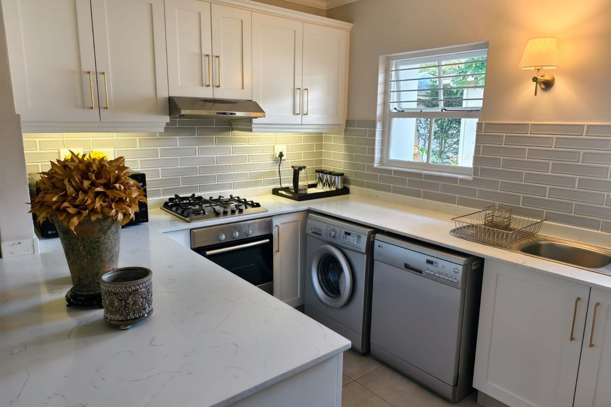 Modern kitchen featuring white shaker cabinetry, quartz countertops, subway tile backsplash, integrated gas hob, oven, and under-cabinet lighting.