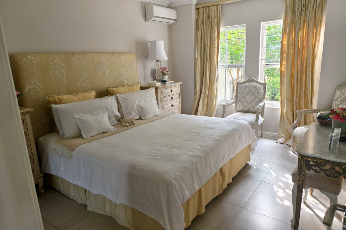 A well-maintained bedroom featuring tiled flooring, recessed downlighting, and a wall-mounted split-system air conditioning unit.