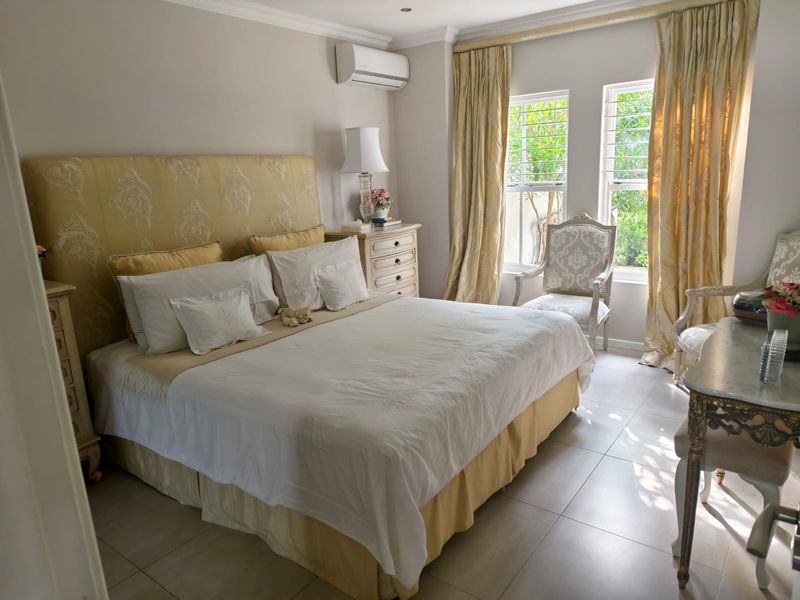 A well-maintained bedroom featuring tiled flooring, recessed downlighting, and a wall-mounted split-system air conditioning unit.