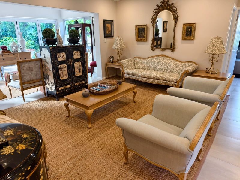 A spacious and well-lit living room featuring large glass sliding doors that provide access to the outdoor area and neutral tiled flooring.