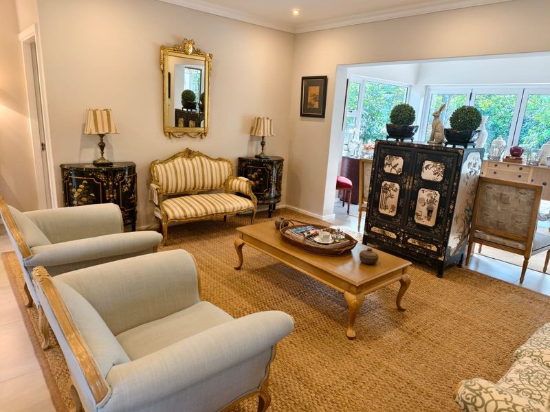 A well-maintained living room featuring crown molding, recessed lighting, and large glass doors that provide ample natural light and garden views.