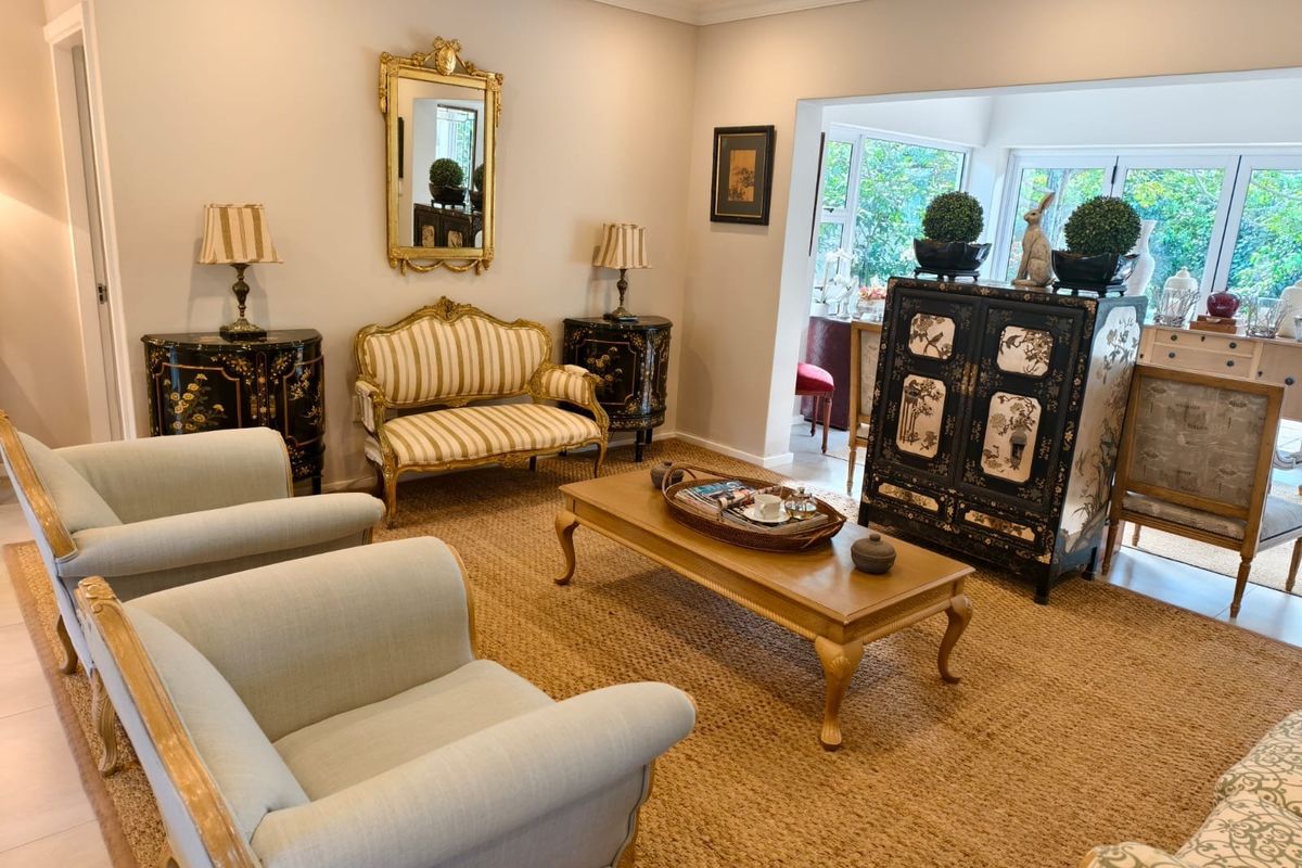 A well-maintained living room featuring crown molding, recessed lighting, and large glass doors that provide ample natural light and garden views.