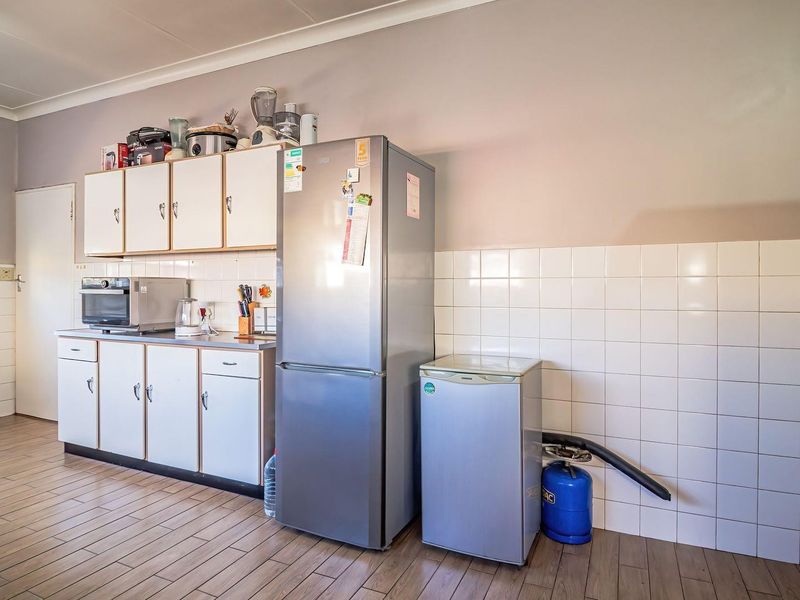A functional kitchen area featuring built-in cabinetry, tiled backsplash, and tiled flooring, providing a practical space for food preparation and storage.