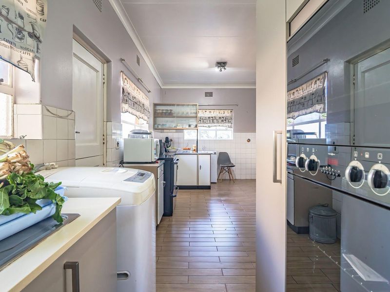 A functional kitchen featuring tiled flooring, built-in cabinetry, a tiled backsplash, and a built-in oven, offering a practical layout for daily meal preparation.