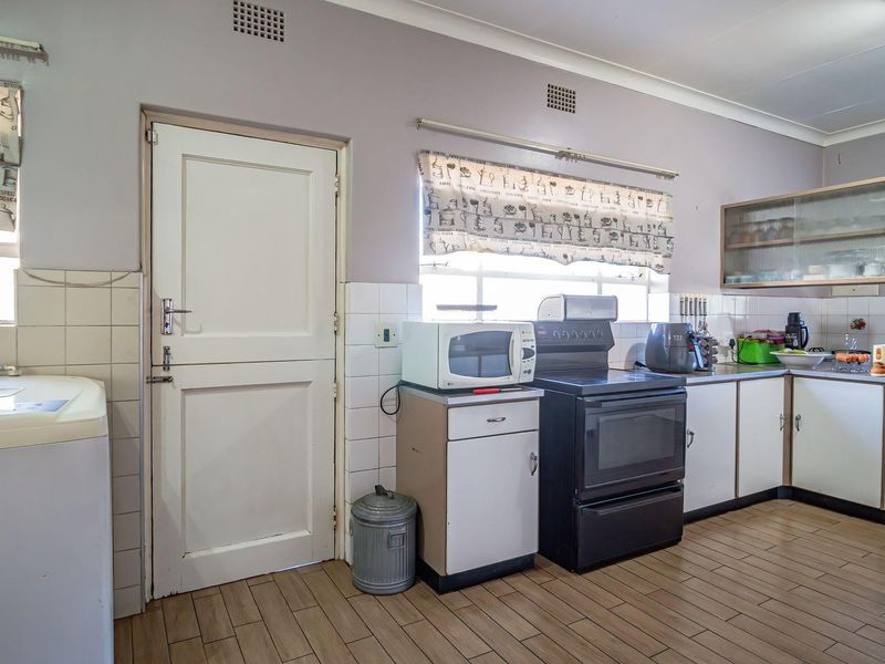 A functional kitchen featuring tiled flooring, built-in cabinetry, and a freestanding oven, offering potential for modernization and aesthetic updates.