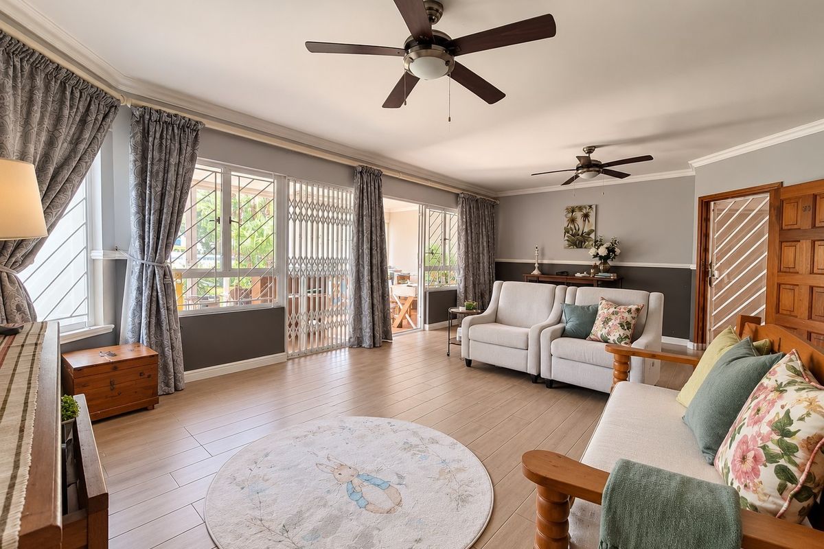 Spacious living room featuring tiled flooring, dual ceiling fans, and large windows with security gates, providing access to an outdoor patio area.