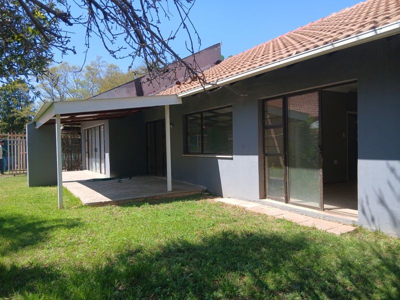 Rear view of the house featuring a covered patio, paved outdoor area, and sliding glass doors leading into the interior living space.