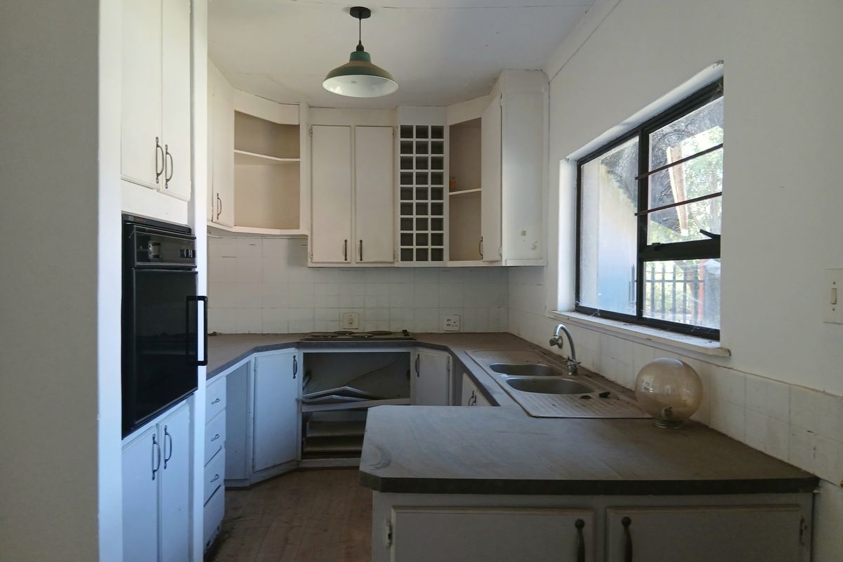 A dated kitchen featuring built-in cabinetry, a double sink, and an integrated oven, requiring renovation to modernize the space and address visible wear.
