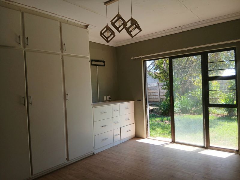 Bedroom featuring built-in cupboards, laminate flooring, and a sliding glass door providing direct access to the garden.