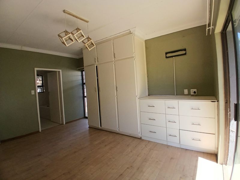 A bedroom featuring laminate flooring, built-in cupboards, and a sliding door providing access to the exterior.