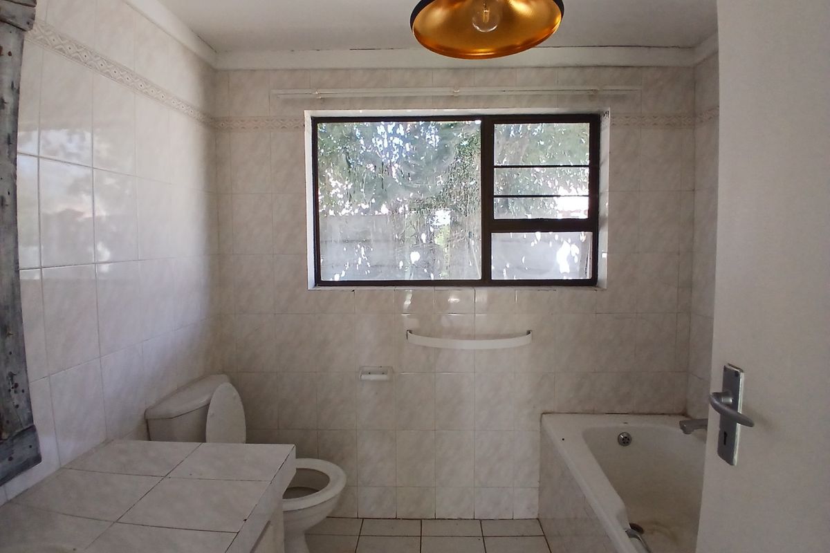 A dated bathroom featuring tiled walls and floors, a built-in vanity, a standard toilet, and a bathtub, offering potential for modernization.