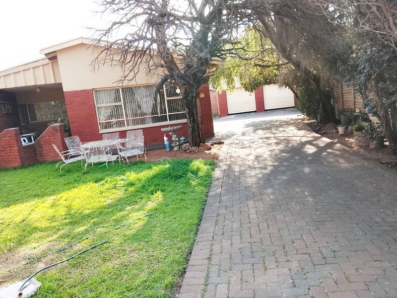 Front view of a single-story house featuring a brick facade, a paved driveway leading to a double garage, and a small front lawn.