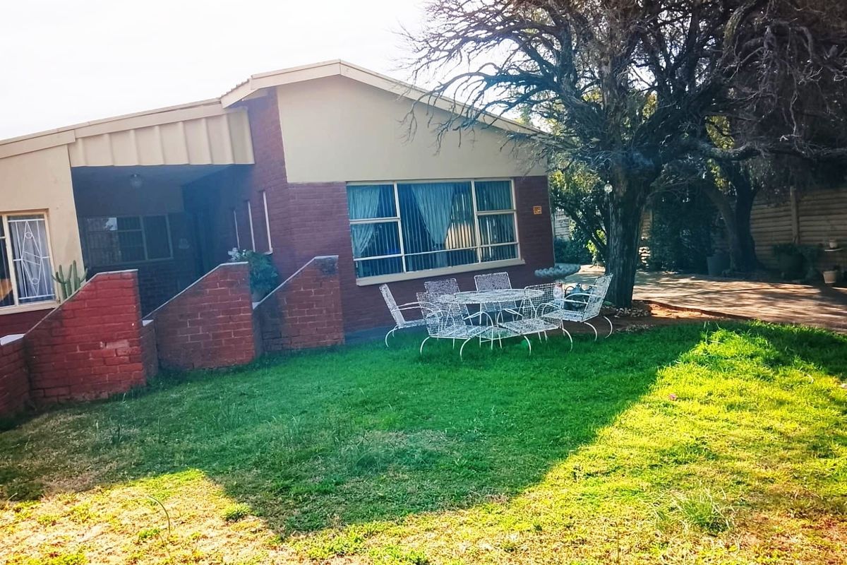 Rear view of the house featuring a brick facade, covered patio area, and established garden space.