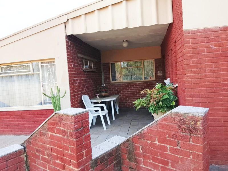 A covered brick patio area featuring paved flooring and direct access to the home's entrance.