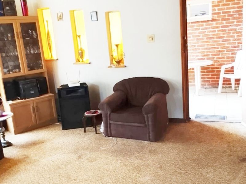 Living room featuring a timber ceiling, recessed wall niches, and carpet flooring, with direct access to an outdoor patio area.
