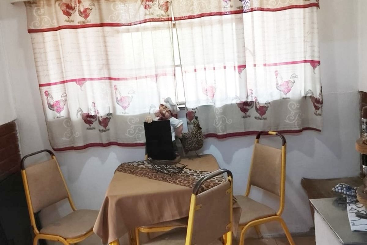 A small kitchen dining area featuring tiled flooring and a window with a curtain rail, currently requiring cosmetic updates to improve the overall aesthetic.