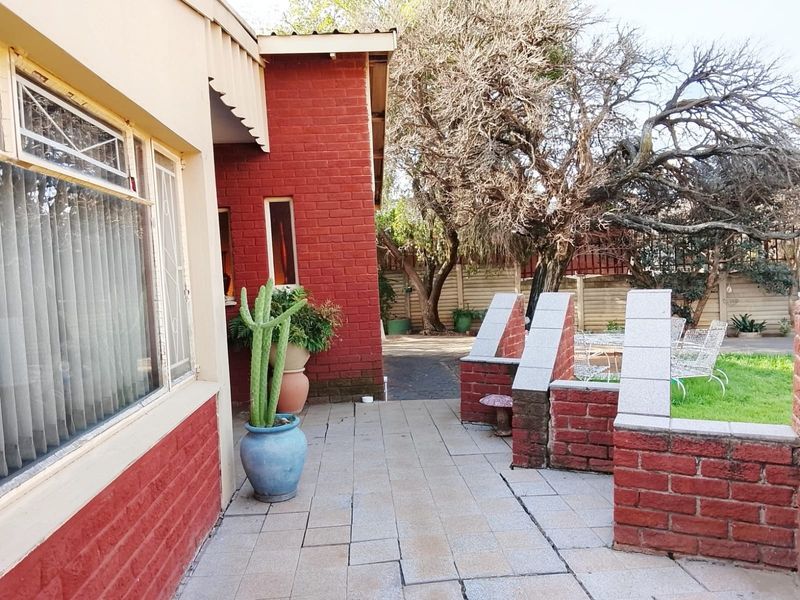 A paved outdoor patio area featuring brick boundary walls and concrete pillars, adjacent to the main house structure.