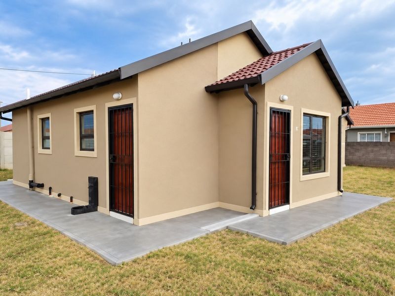 A well-maintained rear exterior view of the house featuring a clean concrete apron, tiled roof, and secure entrance points with security gates.