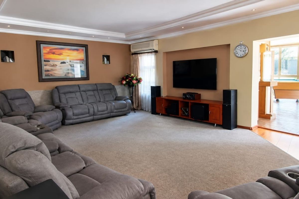 Spacious living room featuring recessed ceiling lighting, cove molding, and a dedicated media wall with integrated air conditioning.