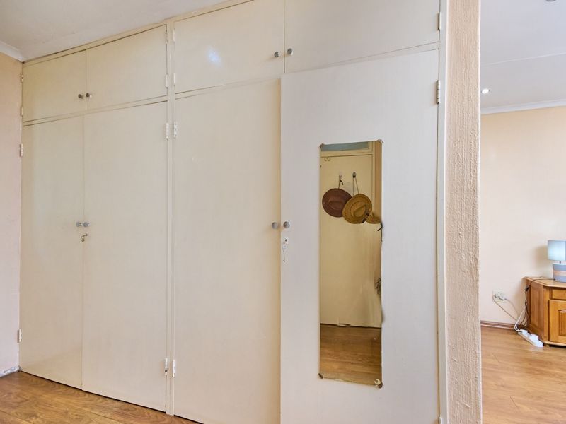 Bedroom featuring extensive built-in cupboards with integrated mirror and laminate flooring, offering practical storage space.