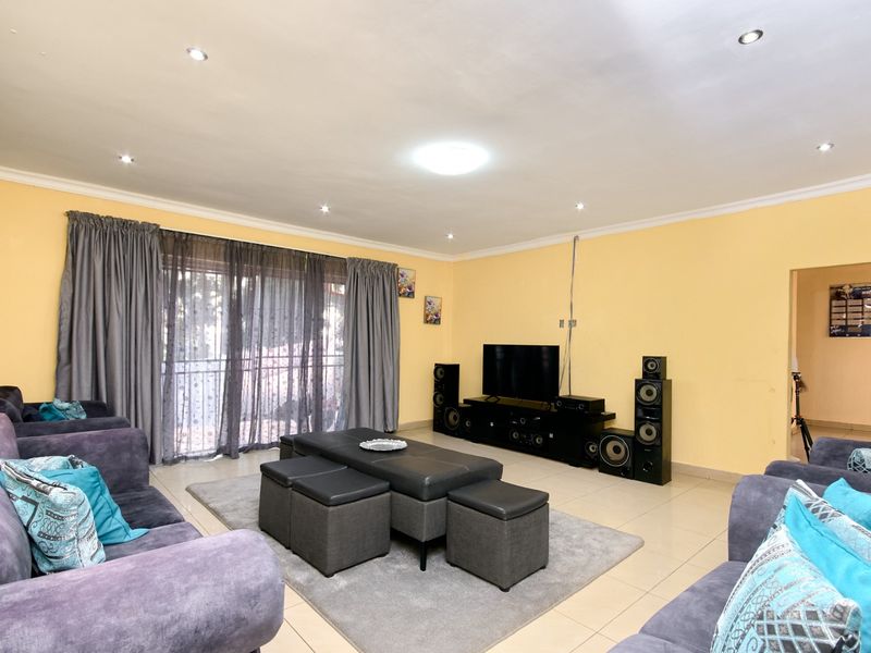 Spacious living room featuring tiled flooring, recessed downlighting, and a sliding glass door providing access to the exterior.
