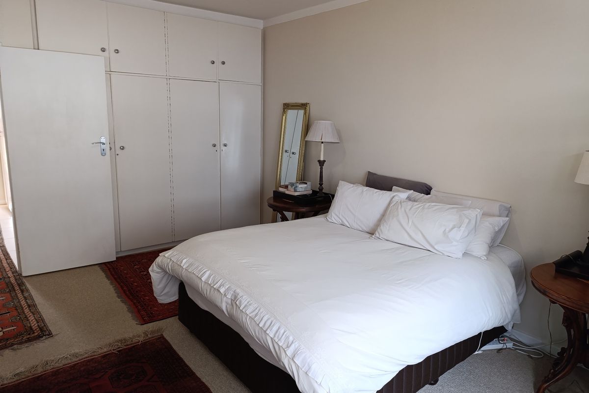 A bedroom featuring neutral walls, carpeted flooring, and ample built-in cupboard storage space.