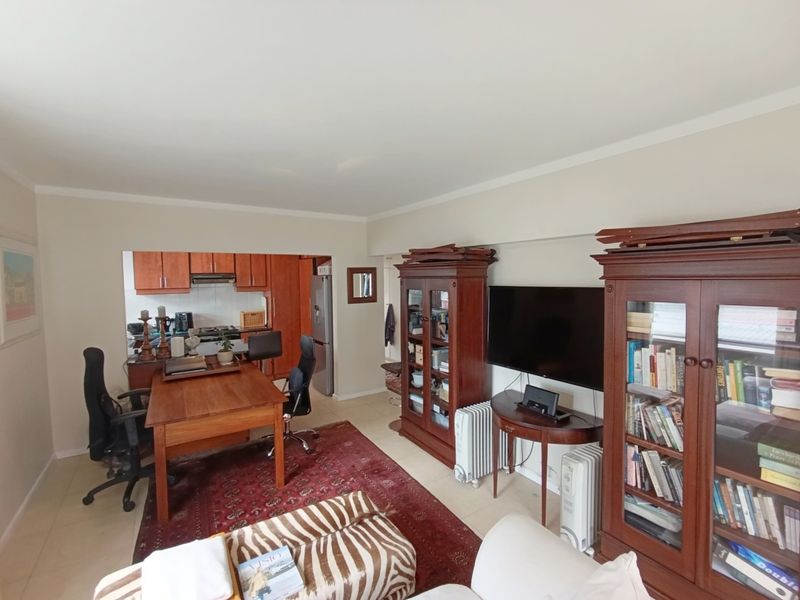 Open plan living area featuring tiled flooring and a connected kitchen with built-in cabinetry and an extractor fan.