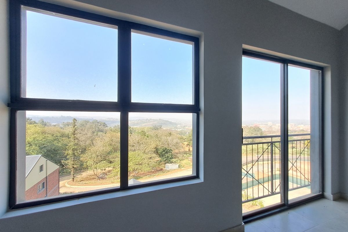 Bright and spacious living area featuring large windows and a sliding door leading to a balcony with scenic views.