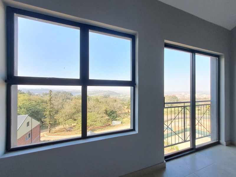 Bright and spacious living area featuring large windows and a sliding door leading to a balcony with scenic views.