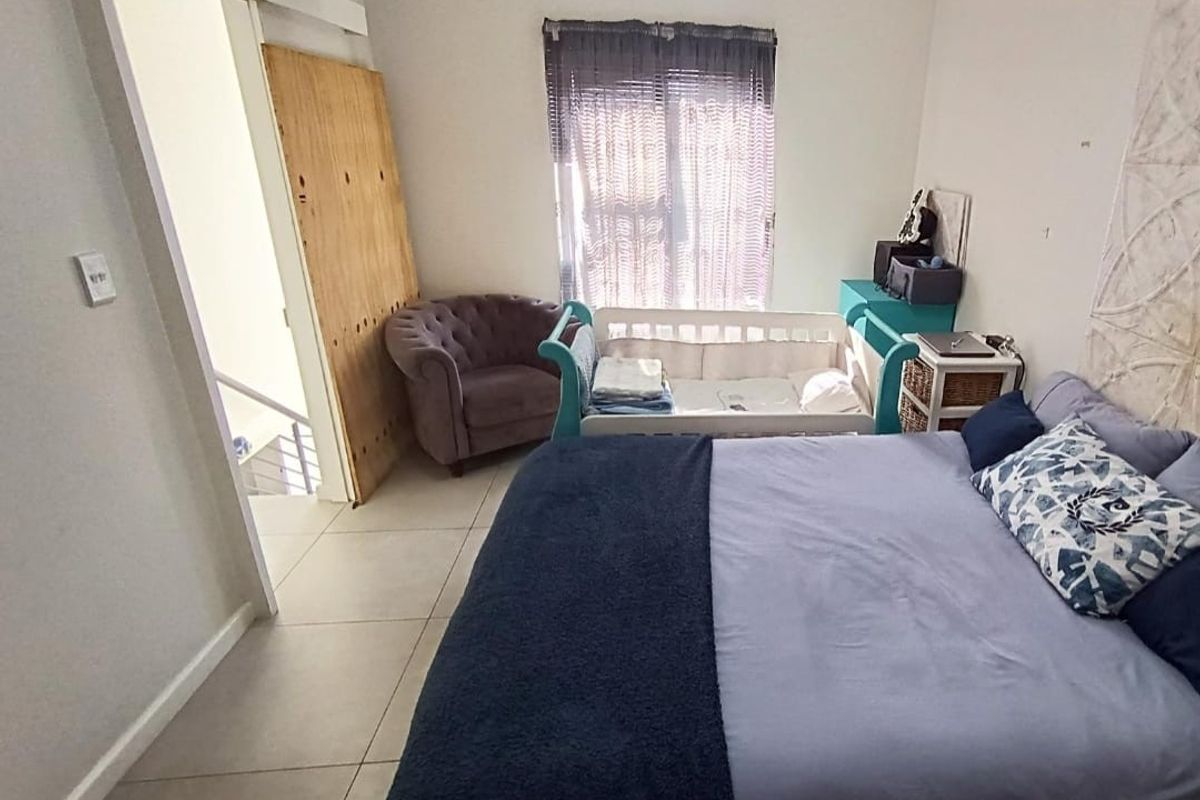 A bedroom featuring tiled flooring and access to an adjacent staircase, currently requiring minor cosmetic repairs to the door and wall finishes.