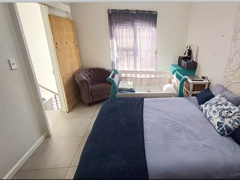 A bedroom featuring tiled flooring and access to an adjacent staircase, currently requiring minor cosmetic repairs to the door and wall finishes.