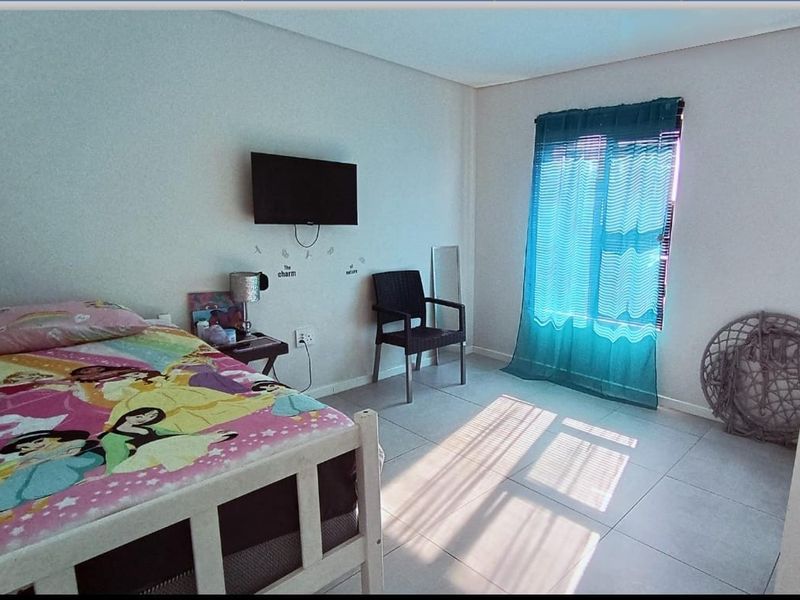 A bedroom featuring tiled flooring and a window with blinds, providing natural light and a functional layout.