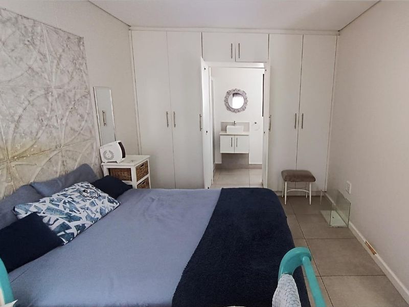A bedroom featuring built-in cupboards and tiled flooring, with direct access to an en-suite bathroom.