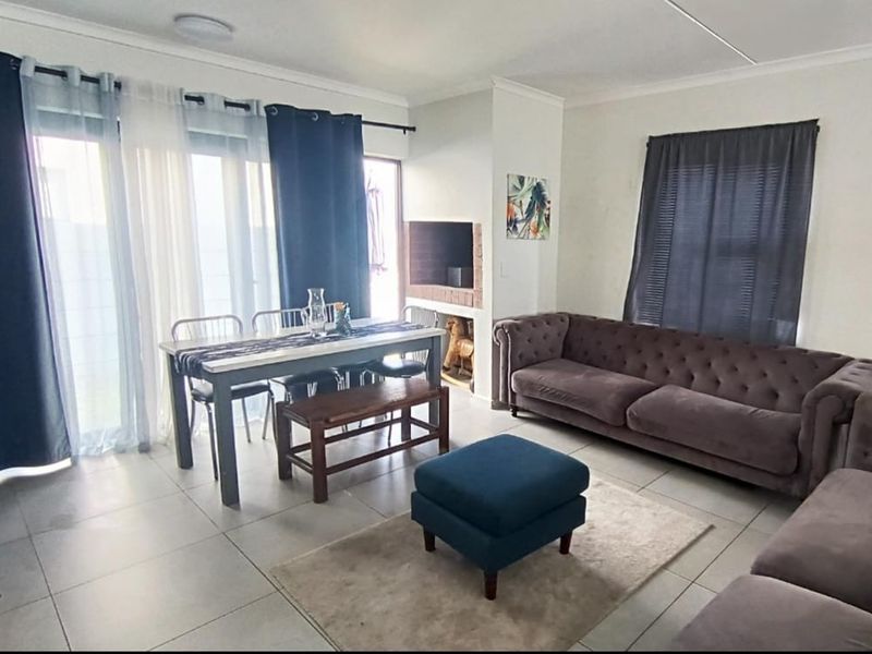 Open-plan living and dining area featuring tiled flooring, a built-in fireplace, and sliding glass doors providing access to the exterior.