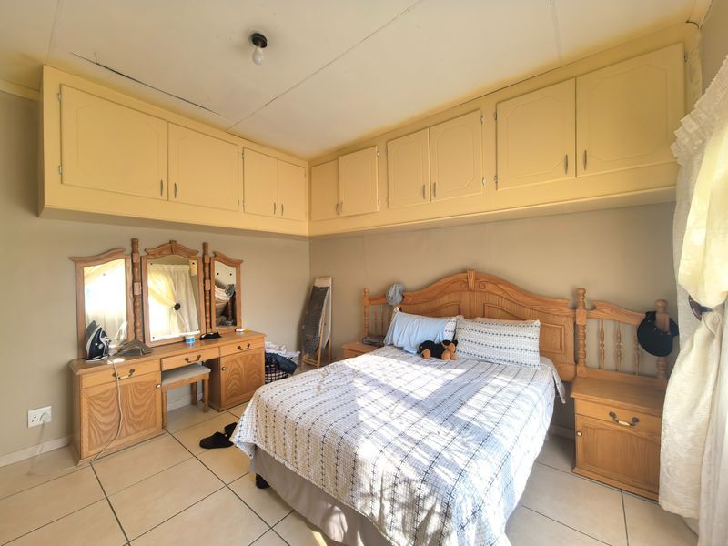 A bedroom featuring extensive built-in overhead cabinetry and tiled flooring, requiring minor ceiling repairs and cosmetic updates to modernize the space.