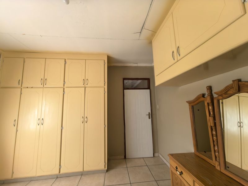 Bedroom featuring extensive built-in cabinetry, overhead storage, and tiled flooring. The room requires cosmetic updates to the ceiling and finishes.