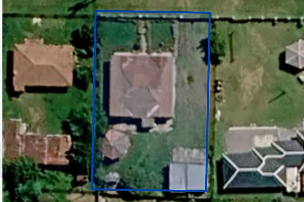 Aerial view of the property showing the house footprint, surrounding garden area, and boundary fencing on the plot.