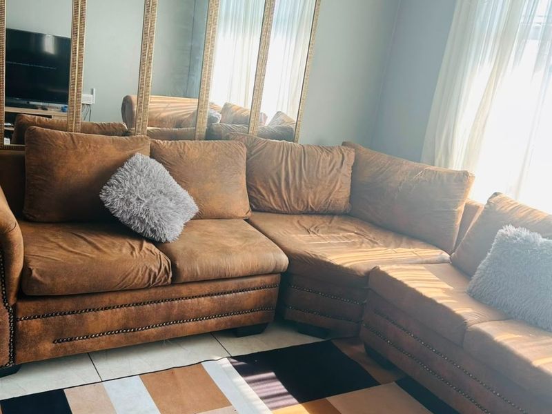 A living room featuring tiled flooring, crown molding, and large decorative wall-mounted mirrors, providing a bright and spacious feel.