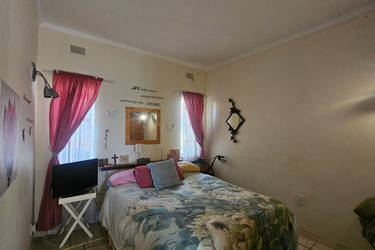 A bedroom featuring tiled flooring and wall-mounted air vents, currently requiring cosmetic updates to the wall finishes.