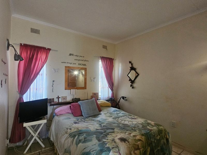 A bedroom featuring tiled flooring and wall-mounted air vents, currently requiring cosmetic updates to the wall finishes.