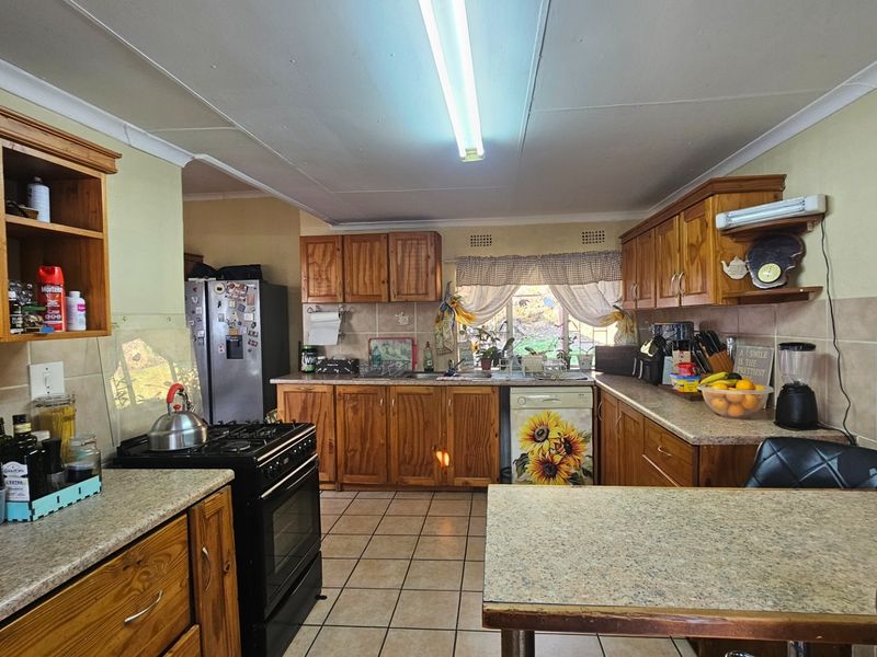 A functional kitchen featuring traditional wooden cabinetry, laminate countertops, tiled flooring, and a tiled backsplash, offering a classic layout with ample storage space.