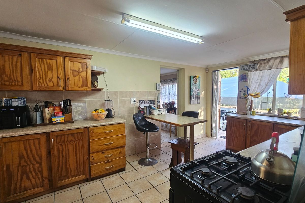 A functional kitchen featuring wooden cabinetry, tiled backsplash, and a gas hob, with direct access to an outdoor area.