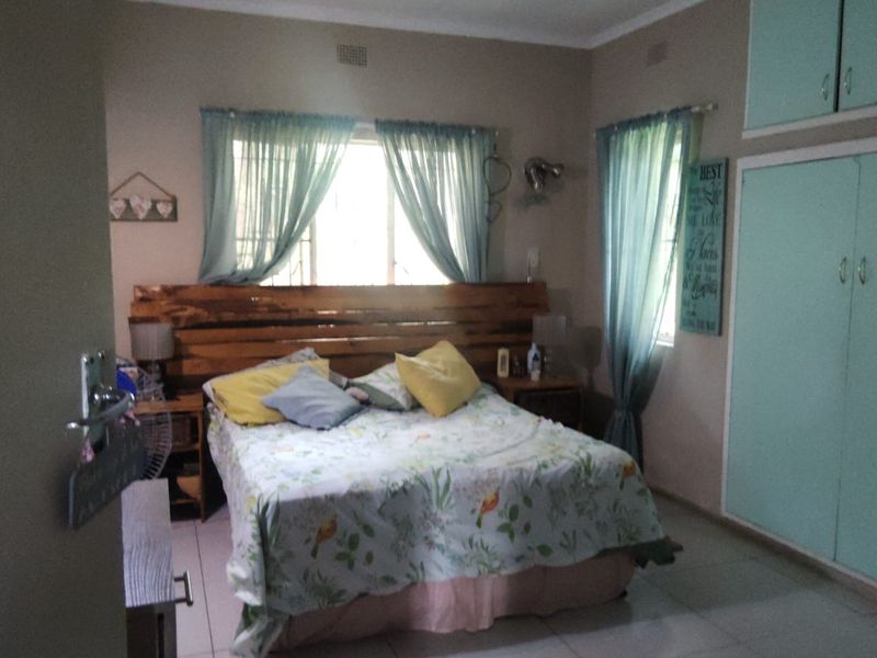 A bedroom featuring built-in cupboards, tiled flooring, and natural light from windows with curtains.