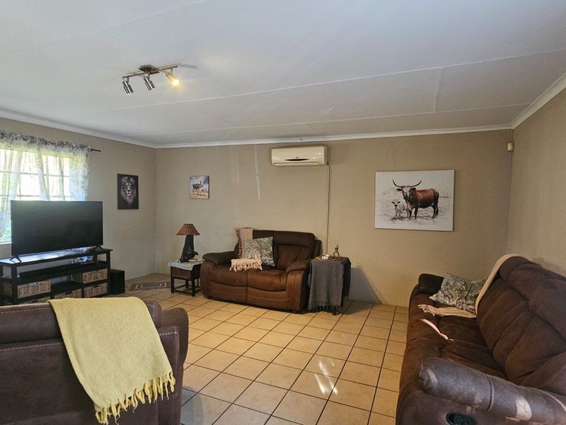 A spacious living room featuring tiled flooring, a wall-mounted air conditioning unit, and track lighting, providing a functional and comfortable living space.