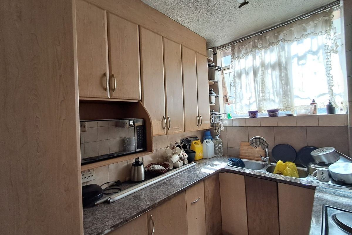A functional kitchen featuring laminate cabinetry, stone-look countertops, a double bowl sink, and built-in microwave, offering potential for a modern renovation.
