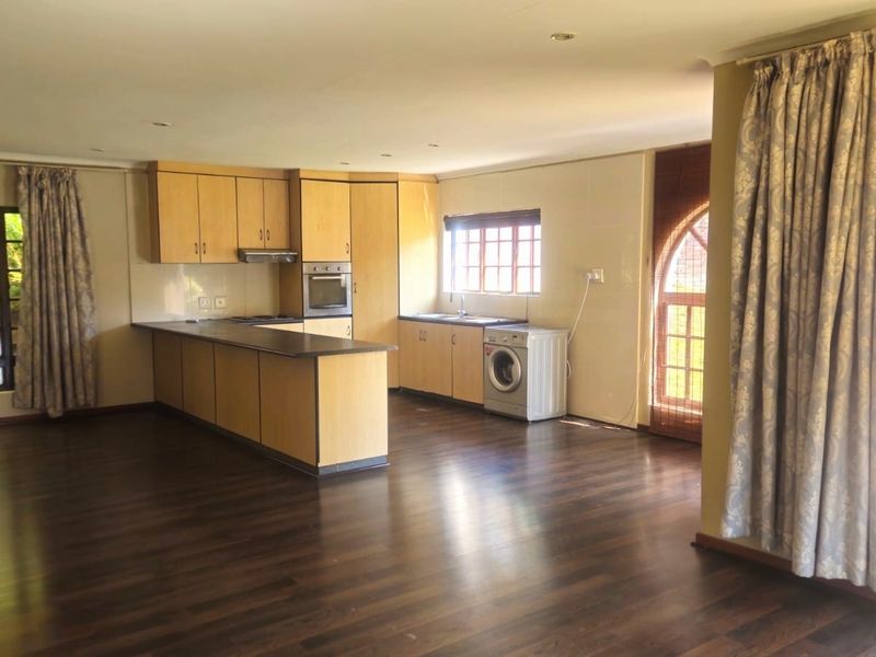 Spacious open-plan living area featuring a functional kitchen with built-in cabinetry, oven, extractor fan, and laminate flooring throughout.