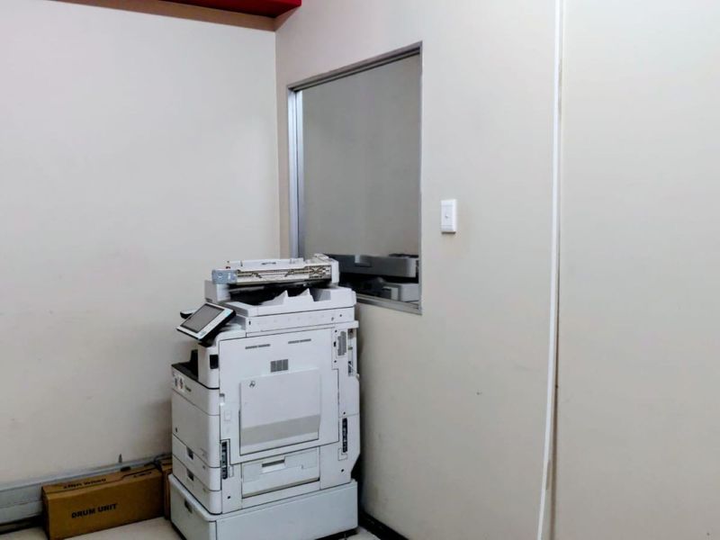 A functional office space featuring a neutral wall finish and an internal window, providing a clean and simple environment for professional use.
