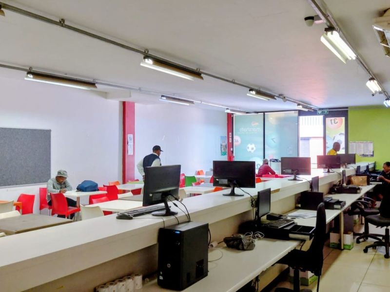 A functional commercial office space featuring a long built-in service counter, tiled flooring, and overhead fluorescent lighting.