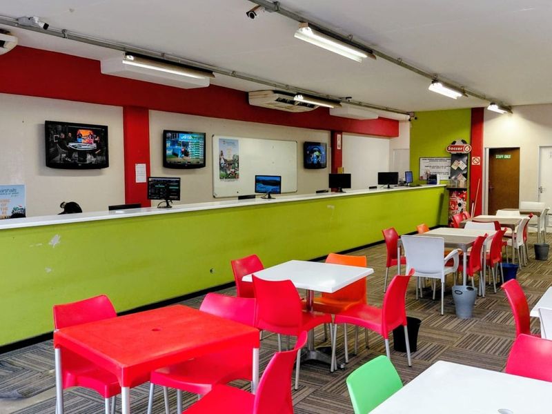 Open-plan commercial betting or service area featuring a long service counter, fluorescent lighting, air conditioning, and carpeted flooring.