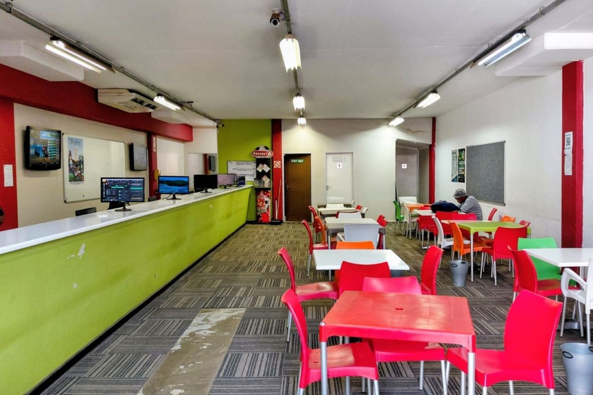Open-plan commercial service area featuring a long service counter, fluorescent lighting, and carpeted flooring, suitable for a betting shop or customer service facility.